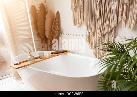 Gemütliches Badezimmer mit großer Badewanne, Pflanzen und rustikaler Dekoration Stockfoto