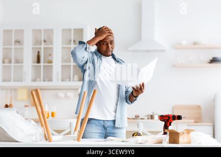 Schwierigkeiten und Probleme bei der Montage neuer Möbel. Verwirrt afroamerikanischen Mann Lesung Anweisung Stockfoto