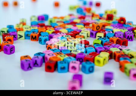Ein Haufen lebendiger, farbiger Buchstabenwürfel, die nach dem Zufallsprinzip zusammengestapelt sind, mit klarer Sichtbarkeit verschiedener Buchstaben, die die Vielfalt in darstellen Stockfoto