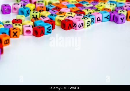 Eine vergrößerte Anordnung von bunten Würfeln mit Buchstaben, die zufällig verstreut sind und Kreativität, Wortbildung und Bildung symbolisieren Stockfoto