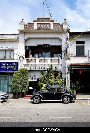 Der alte schwarze Volkswagen Käfer Typ 1 parkt vor einem alten historischen Gebäude in einer asiatischen Stadtstraße Malacca malaysia Stockfoto
