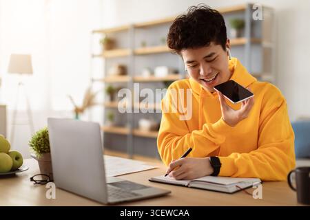 Asian Kerl mit Voice Assistant auf Handy Stockfoto