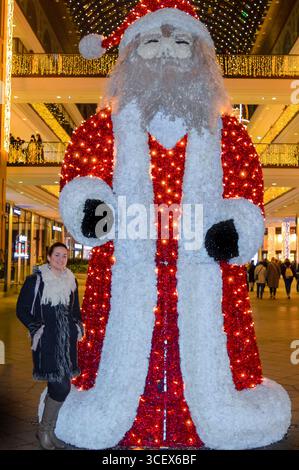 Frau posiert mit riesiger Weihnachtsmannsdekoration in Berlin. Stockfoto