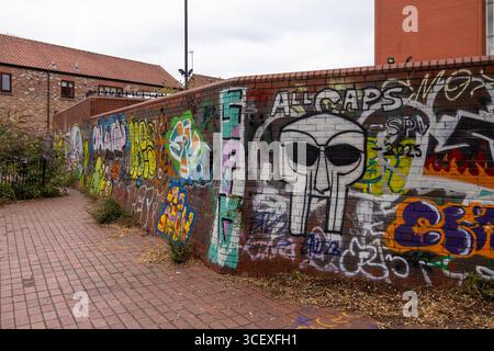 Urbanes Graffiti an einer Ziegelwand mit großem Street Art Design im Skull-Stil mit auffälligen Farben, Tags und Sprühfarben Stockfoto