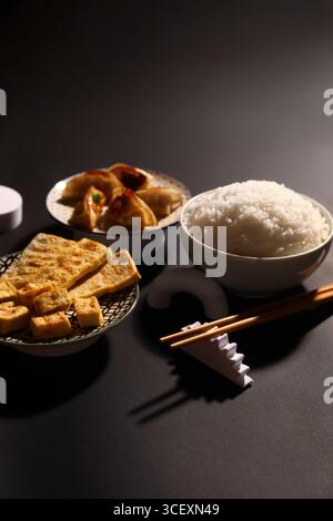 Leckeres chinesisches Essen und Essstäbchen auf dunklem Hintergrund Stockfoto