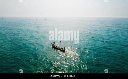 Aus der Vogelperspektive eines einsamen Holzbootes, das durch das türkisfarbene Wasser schneidet und das strahlende Licht der Sonne reflektiert, die Lage wurde nicht berücksichtigt. Stockfoto