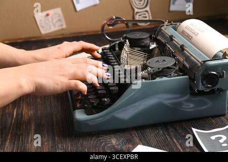 Frau, die auf Retro-Schreibmaschine auf Holztisch tippt, Nahaufnahme Stockfoto