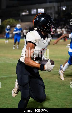 American Football fokussierte Athletin läuft in voller Geschwindigkeit Fußball, die Augen sind im Moment des Outdoor-Spiels mit hohem Einsatz im Auge – purer Grip und Entschlossenheit Stockfoto