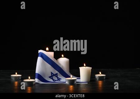 Brennende Kerzen und Flagge Israels auf dunklem Hintergrund. Holocaust-Gedenktag Stockfoto