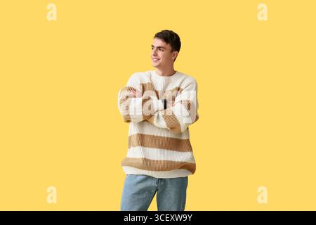 Hübscher junger Mann in stilvollem gestreiftem Pullover auf gelbem Hintergrund Stockfoto