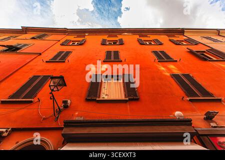 Bologna, italien 19. august 2025: Flacher Blick auf ein typisches oranges Gebäude mit dunklen Holzläden in bologna, italien, an einem sonnigen Tag Stockfoto