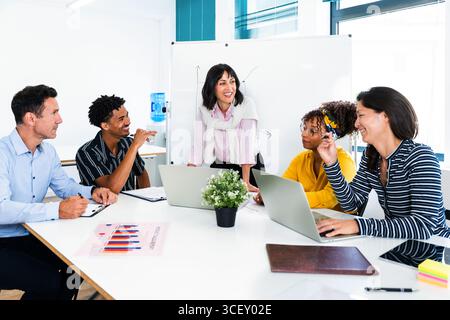 Multi-ethnische Geschäftsteams arbeiten während der Besprechung in modernen Büros an Projekten zusammen, verwenden Laptops und analysieren Diagramme, um Teamarbeit zu fördern und zu erreichen Stockfoto