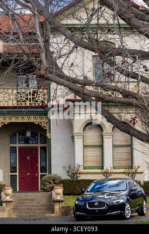 Black Jaguar parkte vor einem historischen viktorianischen Haus mit blattlosen Bäumen in Hobart, Tasmanien. Stockfoto