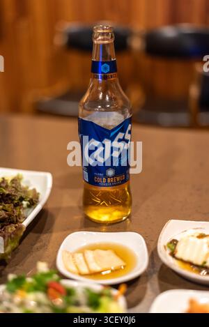 Eine Flasche frisches Cass-Bier auf einem Tisch mit Speisen in einem koreanischen Restaurant in Seoul, Südkorea am 4. November 2023 Stockfoto