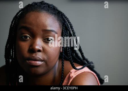Horizontales Nahporträt einer schönen jungen Schwarzen Frau mit Afro-Flechten, die in die Kamera blickt Stockfoto