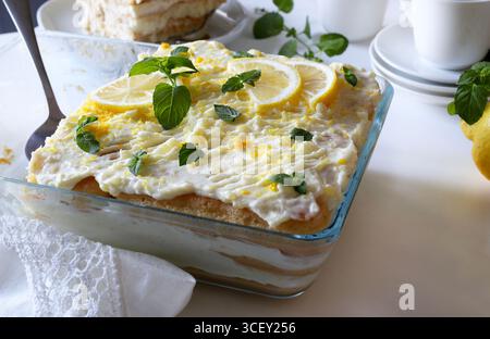 Italienisches Zitronentiramisu. Zitronentiramisu mit Marienfinger und Mascarponcreme auf einem weißen Tisch, frische Minzdekoration. Sommerdessert. Direkt darüber. Stockfoto