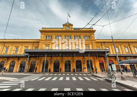 Modena, italien 20. august 2025: Die Fassade des Bahnhofs modena in italien zeigt die Nationalflagge und einen bewölkten Himmel darüber Stockfoto