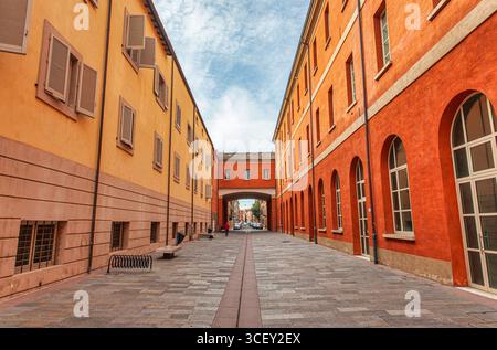 Modena, italien 20. august 2025: Leere Straße in modena, italien, mit farbenfrohen Gebäuden und einem Bogengang, der zwei Gebäude verbindet Stockfoto