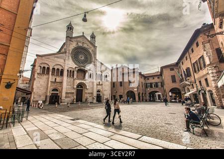 Modena, italien 20. august 2025: Touristen wandern auf der piazza grande mit der Kathedrale von modena im Hintergrund an einem bewölkten Tag in modena, italien Stockfoto