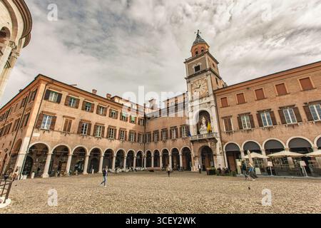 Modena, italien 20. august 2025: Touristen gehen auf der piazza grande mit dem palazzo comunale Uhrenturm im Hintergrund, modena, italien Stockfoto