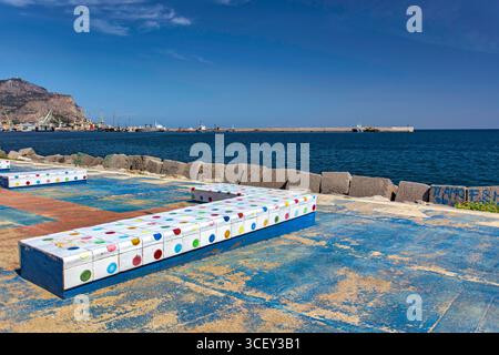 Palermo, italien 20. august 2025: Malerischer Blick auf farbenfrohe Bänke am Hafen von palermo, sizilien, mit monte pellegrino im Hintergrund Stockfoto