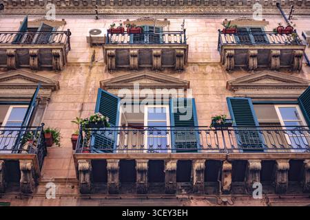 Palermo, italien 20. august 2025: Offene Fenster und blumengefüllte Balkone verleihen der traditionellen Gebäudefassade in palermo, italien, Charme Stockfoto