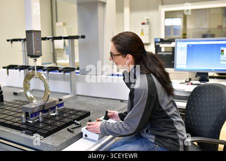 Frau in der Qualitätskontrolle in der Industrie arbeiten - Messung eines Werkstücks Stockfoto