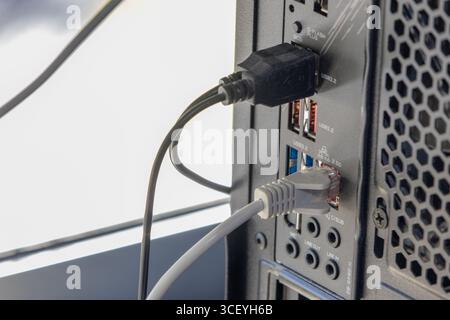 USB- und ethernet-Kabel werden an die Anschlüsse auf der Rückseite des Computers angeschlossen, um die Datenübertragung und Netzwerkverbindung zu ermöglichen Stockfoto