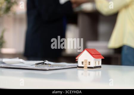 Verkauf Von Immobilien. Ein Musterhaus auf einem Tisch mit Papierkram in einem Immobilienbüro. Stockfoto