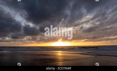 Sonnenuntergang mit goldenem Himmel über dem Strand praia grande in Sintra, Portugal Stockfoto