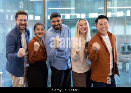 Ein zufriedenes und vielfältiges Team von Kollegen feiert mit Enthusiasmus und Positivität eine erfolgreiche Leistung am Arbeitsplatz. Die Gruppe strahlt Teamarbeit, Zusammenarbeit und gegenseitigen Respekt aus Stockfoto