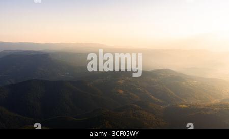 Golden Haze hüllt die Berglandschaft in warme Abendtöne und schafft eine traumhafte und friedliche Atmosphäre Stockfoto