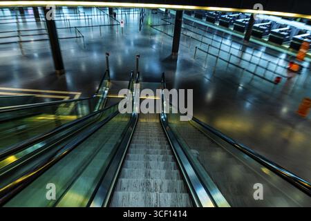 Beleuchteter Flughafen Zürich mit Eskalator und Check-in-Schalter in unscharfer Bewegung bei Nacht im Flughafen Kloten, Zürich, Kanton Zürich, Switzer Stockfoto
