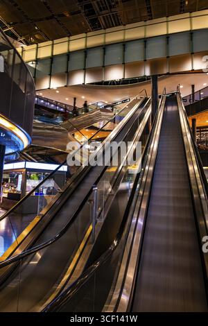 Beleuchteter Flughafen Zürich mit Eskalator in Bewegung bei Nacht im Flughafen Kloten, Zürich, Kanton Zürich, Schweiz Stockfoto