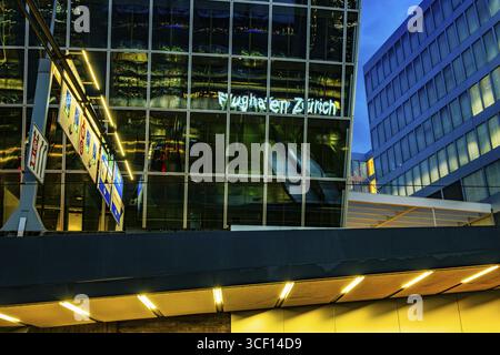Beleuchtetes Schild zum Flughafen Zürich reflektiert nachts auf einem modernen Bürogebäude im Flughafen Kloten, Zürich, Kanton Zürich, Schweiz Stockfoto