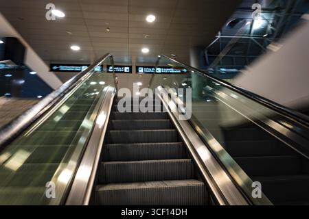 Beleuchteter Flughafen Zürich mit Eskalator in unscharfer Bewegung bei Nacht im Flughafen Kloten, Zürich, Kanton Zürich, Schweiz Stockfoto
