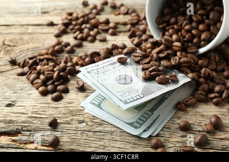 Dollarscheine, Kaffeebohnen und Tasse auf Holztisch, Nahaufnahme Stockfoto
