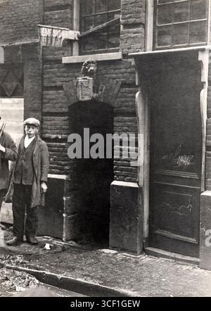 Ein jüdischer Junge steht vor dem Tor zur Red Lion Passage in der Valkenburgerstraat, Amsterdam. Das Foto zeigt ein jüdisches Viertel vor der Stadterneuerung im frühen 20. Jahrhundert. Stockfoto