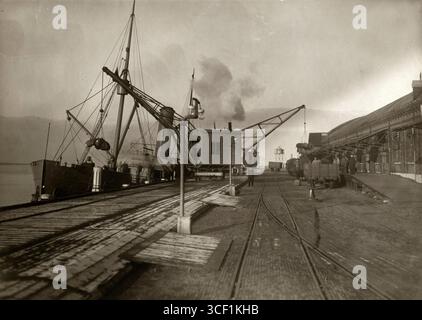 Im Hafen von Hoek van Holland wird ein Paketschiff entladen, mit Kränen, die die Fracht für den weiteren Transport in Postzüge transportieren, 1916. Stockfoto