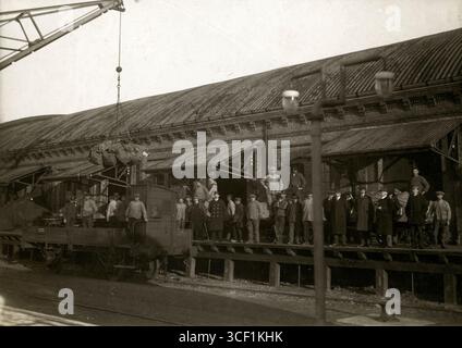 Eine Gruppe von Männern, darunter Hafenarbeiter, steht an einem Lagerhaus im Hafen von Hoek van Holland und bearbeitet Post für britische Kriegsgefangene während des Ersten Weltkriegs 1916. Stockfoto