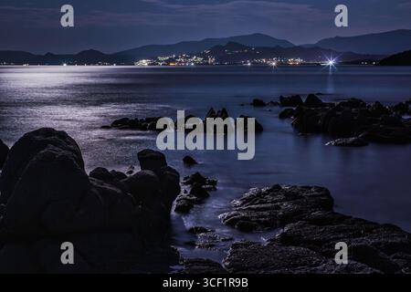 Ruhige Nachtszene am Strand des Capo Ferrato in sardinien, italien, mit Mondlicht, das sich auf das ruhige Meer reflektiert und die Küste beleuchtet Stockfoto