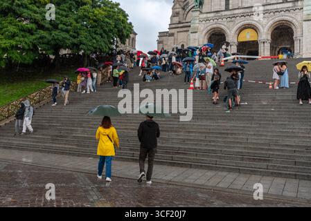 Leute mit Regenschirmen im starken Regen in Montmartre, dem 18. Arrondissement von Paris Stockfoto
