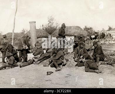 Erschöpfte türkische Soldaten ruhten am Straßenrand während des Ersten Balkankrieges 1912. Im Hintergrund befinden sich Wagen und Strohdachhütten. In diesem Krieg kämpften die balkanstaaten gegen das Osmanische Reich. Stockfoto