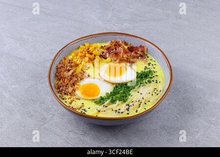 Cremiger Käse-Ramen mit Speck, weich gekochten Eiern und Gemüse Stockfoto