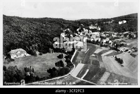 Luftaufnahme von Eppenhain in Taunus, aufgenommen um 1935. Das Bild fängt das Dorf und seine umliegende natürliche Schönheit ein und zeigt seine Lage zwischen drei Bergen. Stockfoto