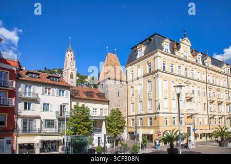 Der mittelalterliche Zwölferturm erhebt sich zwischen historischen und eleganten Gebäuden in der Altstadt von Meran, mit dem Glockenturm der Nikolaikirche im Hintergrund. Meran, Südtirol, Trentino-Südtirol, Norditalien Stockfoto
