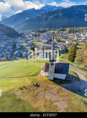 Blick aus der Vogelperspektive auf die Kirche der Beata Vergine della Salute auf dem Hügel mit Blick auf das Dorf Caviola, mit seinen Dächern und Häusern eingebettet zwischen alpinen Wiesen und Wäldern. Valle del Biois, Falcade, Provinz Belluno, Region Veneto, Nordosten Italiens Stockfoto