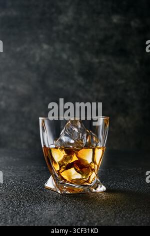 Whiskey mit Eis oder Schnaps im Glas mit Zigarre auf schwarzem Hintergrund. Whisky mit Eis im Glas. Whiskey oder Brandy. Selektiver Fokus. Stockfoto