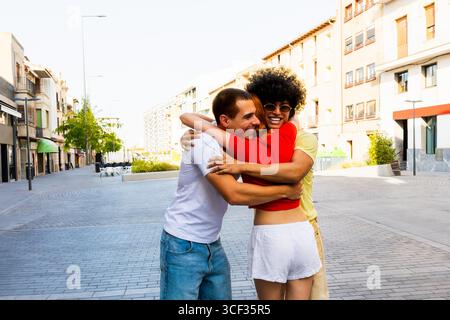 Fröhliche Freunde umarmen sich in der Stadtstraße, um Freundschaft und Freude zu empfangen Stockfoto