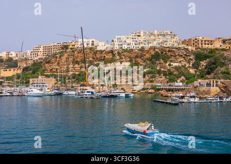 Gozo, Malta - 23. Juni 2021: Hafen mit Booten und Blick auf die Kirchen auf dem Hügel von Gozo. Stockfoto